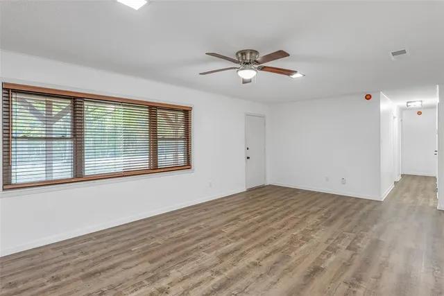 a view of empty room with wooden floor and fan