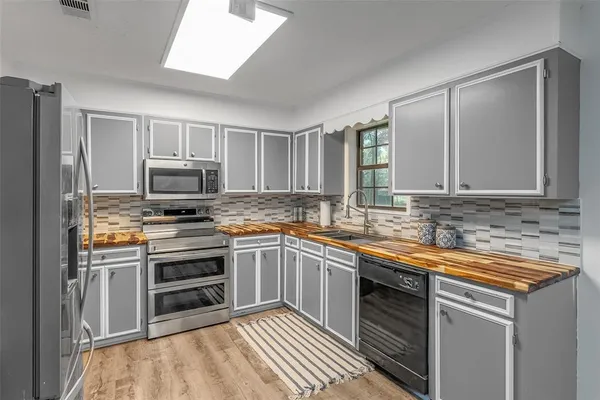a kitchen with sink a microwave and cabinets