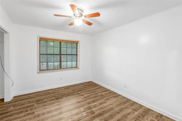 an empty room with a window and ceiling fan
