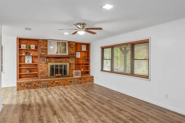 a view of a livingroom with wooden floor a ceiling fan and windows