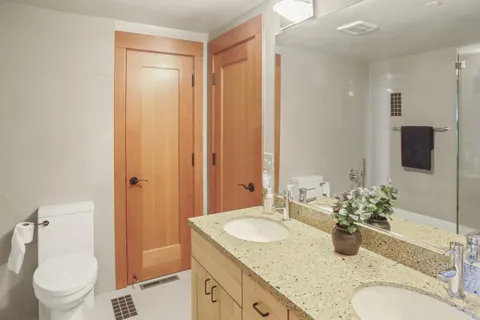a bathroom with a granite countertop sink a toilet and a large mirror