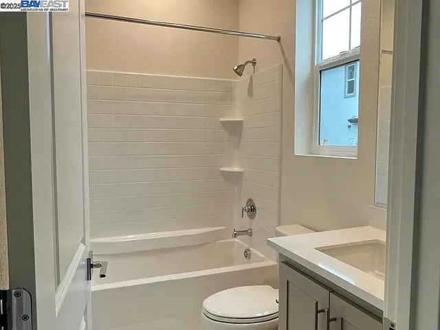 a bathroom with a granite countertop bathtub shower sink vanity and toilet