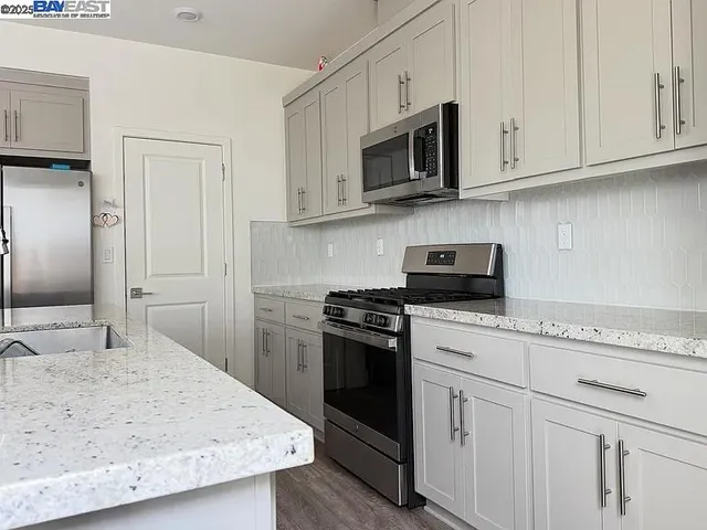 a kitchen with stainless steel appliances granite countertop white cabinets sink and a granite counter top