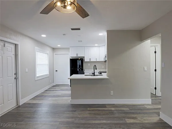 a view of kitchen with stainless steel appliances granite countertop a stove top oven a refrigerator a sink and a dining table with wooden floor