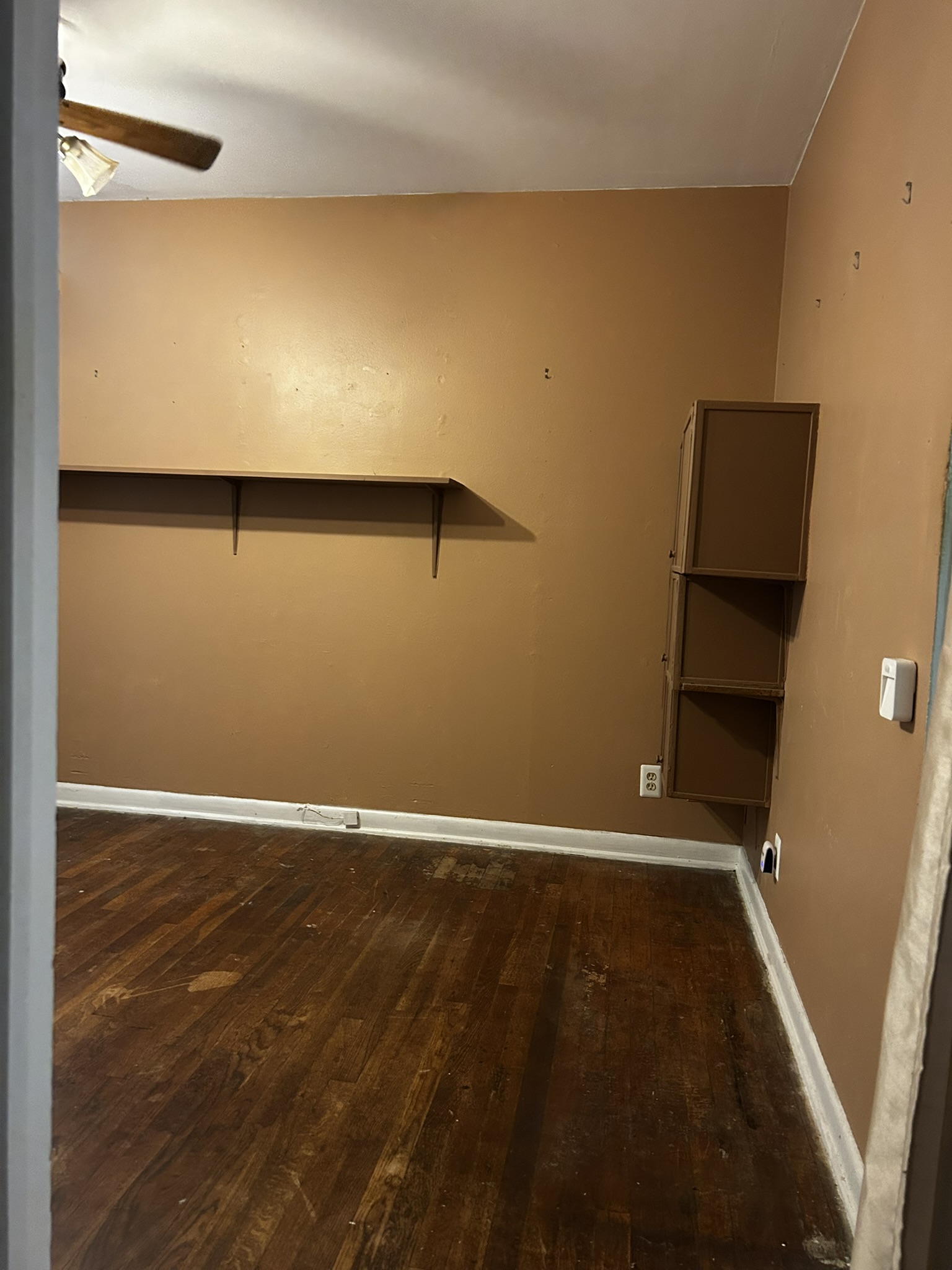 5702 Duval Street Austin, TX 78752 - Photo 31 of 31 Room featuring wood-finish flooring, a ceiling fan with light fixture, built-in shelving, and wall-mounted cabinetry