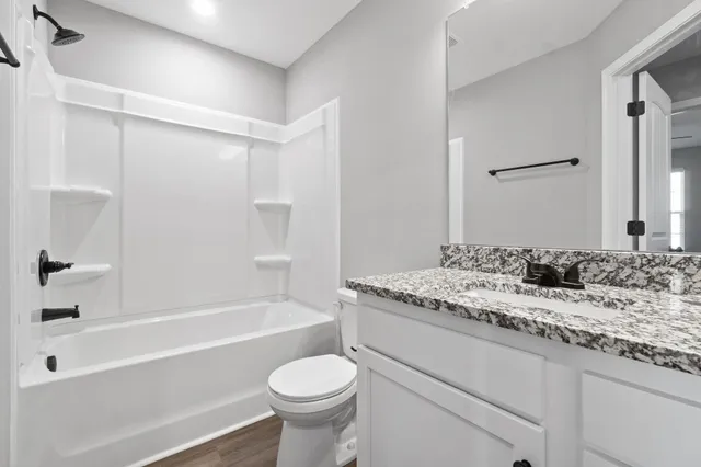 a bathroom with a granite countertop sink toilet mirror and bathtub