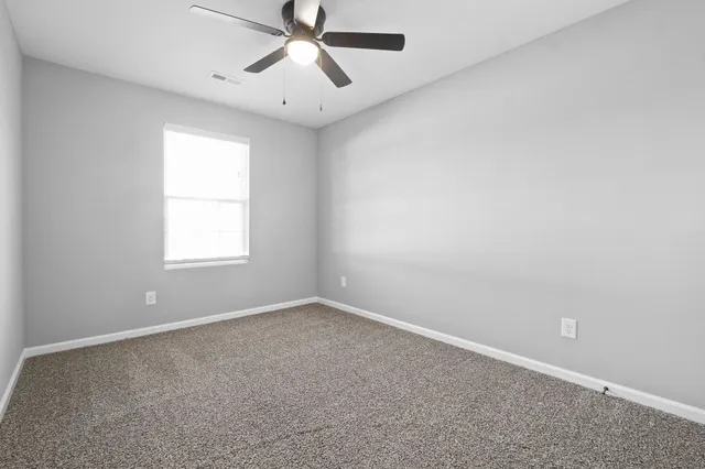 an empty room with a window and a fan