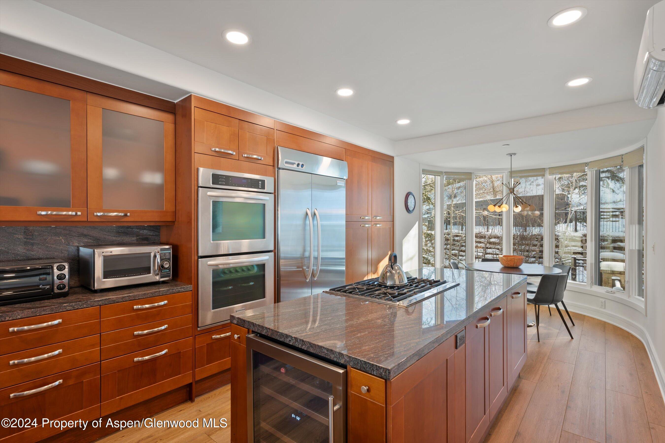 381 Ridge Road, Unit A5 Snowmass Village, CO 81615 - Photo 11 of 43 a kitchen with stainless steel appliances granite countertop a stove top oven a sink dishwasher a dining table and chairs with wooden floor