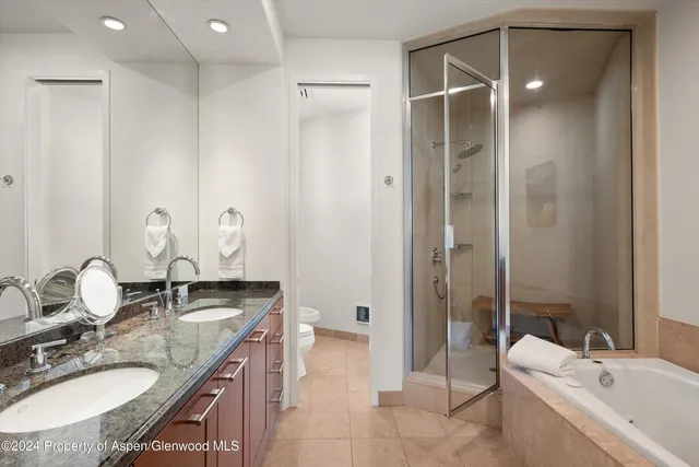 a bathroom with a granite countertop sink a toilet and shower