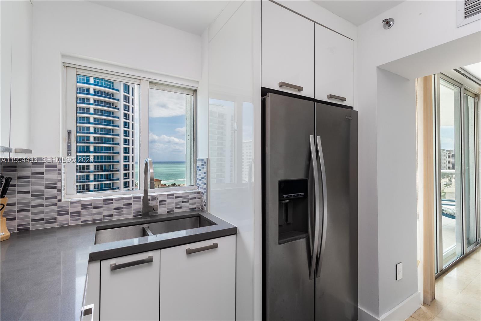 5900 Collins Avenue, Unit 1207 Miami Beach, FL 33140 - Photo 11 of 25 a kitchen with stainless steel appliances granite countertop a refrigerator and a sink