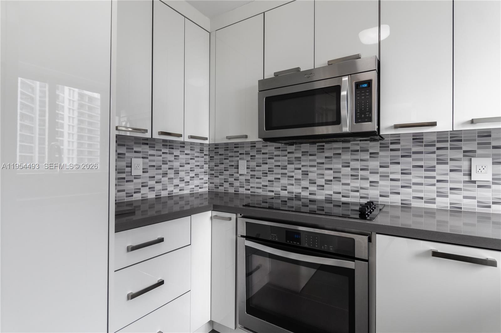 5900 Collins Avenue, Unit 1207 Miami Beach, FL 33140 - Photo 12 of 25 a kitchen with stainless steel appliances granite countertop a sink stove and microwave