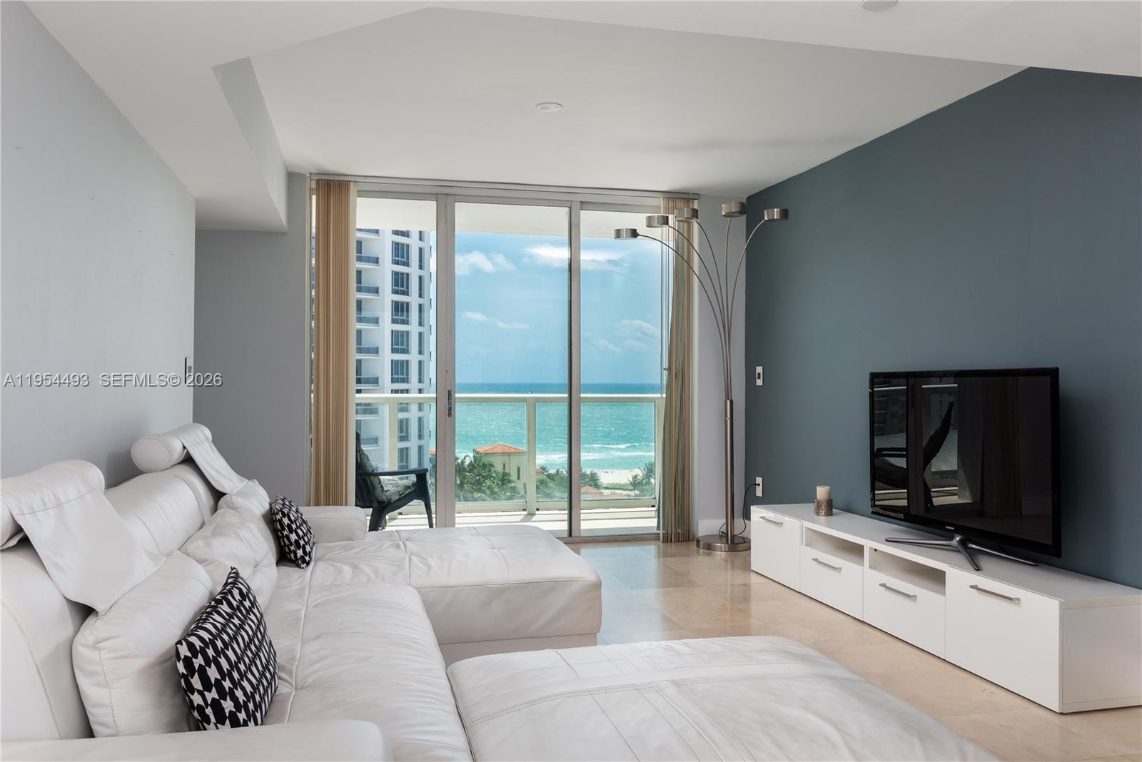 5900 Collins Avenue, Unit 1207 Miami Beach, FL 33140 - Photo 6 of 25 a living room with furniture a flat screen tv and a large window