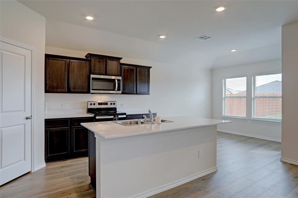 6517 Waterfall Lane Princeton, TX 75407 - Photo 5 of 19 a kitchen with kitchen island granite countertop a sink wooden floor and stainless steel appliances
