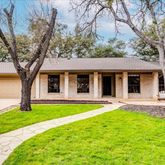 a front view of a house with a yard and large tree