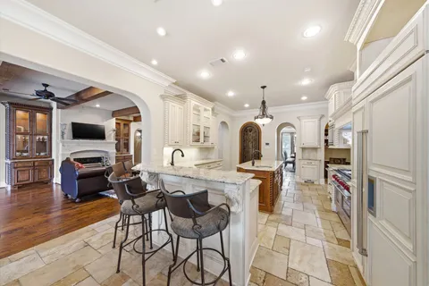 a kitchen with stainless steel appliances kitchen island granite countertop a refrigerator and chairs