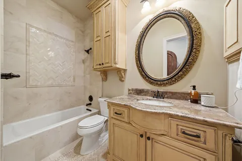 a bathroom with a granite countertop toilet a sink and a mirror