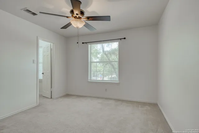an empty room with a window and a fan