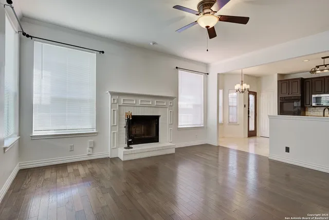 a view of a livingroom with a fireplace a ceiling fan and windows