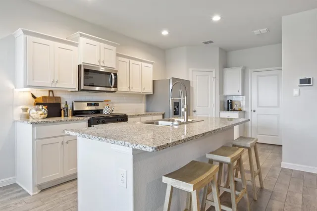 a kitchen with stainless steel appliances granite countertop a sink a stove a microwave a refrigerator and cabinets