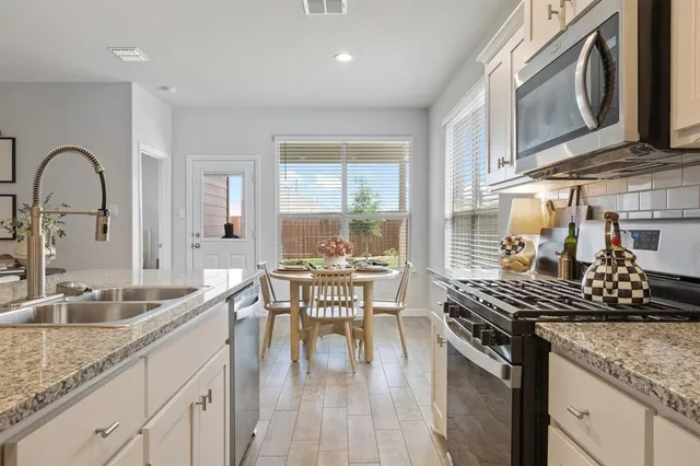 a kitchen with stainless steel appliances granite countertop a sink stove and cabinets