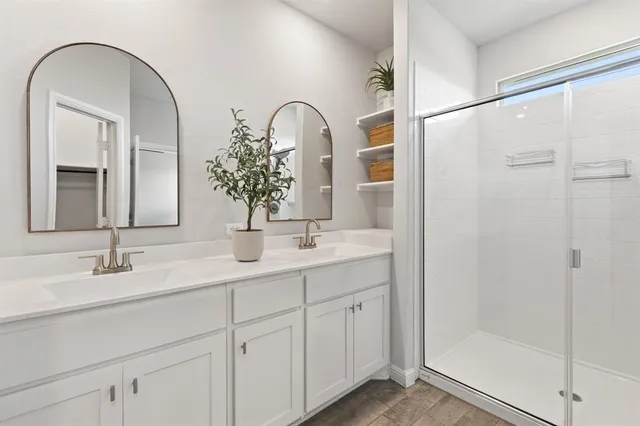 a bathroom with a double vanity sink mirror and shower