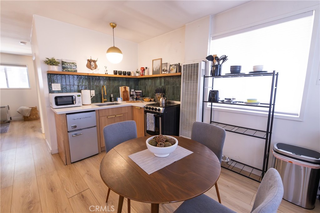 376 Riverside Avenue Sugarloaf, CA 92386 - Photo 10 of 28 a kitchen with stainless steel appliances granite countertop a sink dishwasher a stove a refrigerator and a dining table with wooden floor