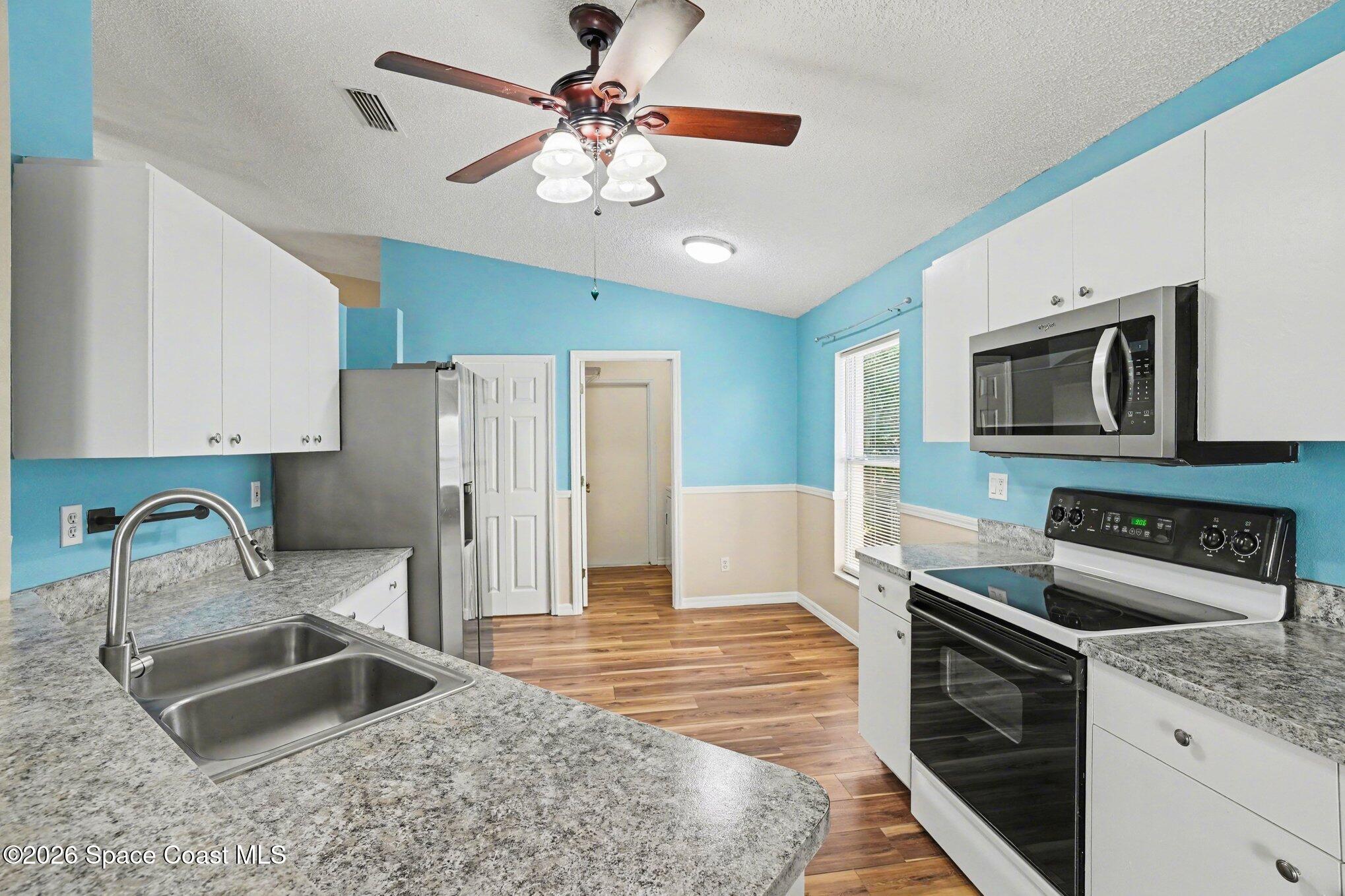 2547 Deercroft Drive Melbourne, FL 32940 - Photo 12 of 35 a kitchen with stainless steel appliances granite countertop a sink refrigerator stove and microwave