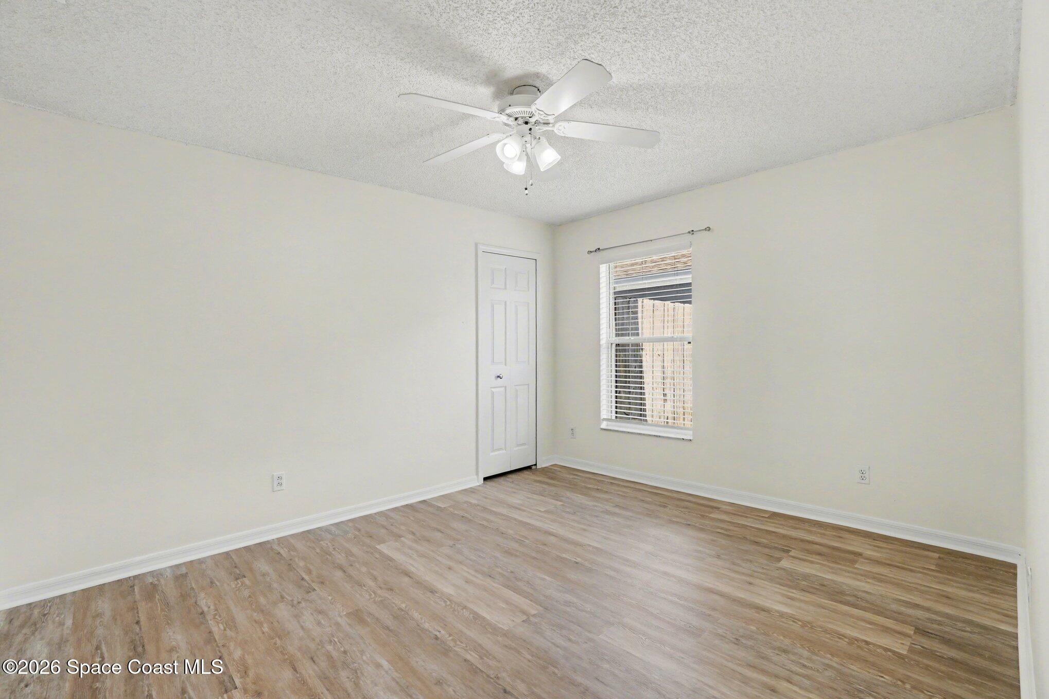 2547 Deercroft Drive Melbourne, FL 32940 - Photo 19 of 35 a view of an empty room with wooden floor and a ceiling fan