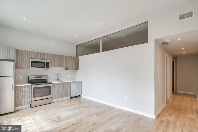 a view of a kitchen with cabinets stainless steel appliances and wooden floor