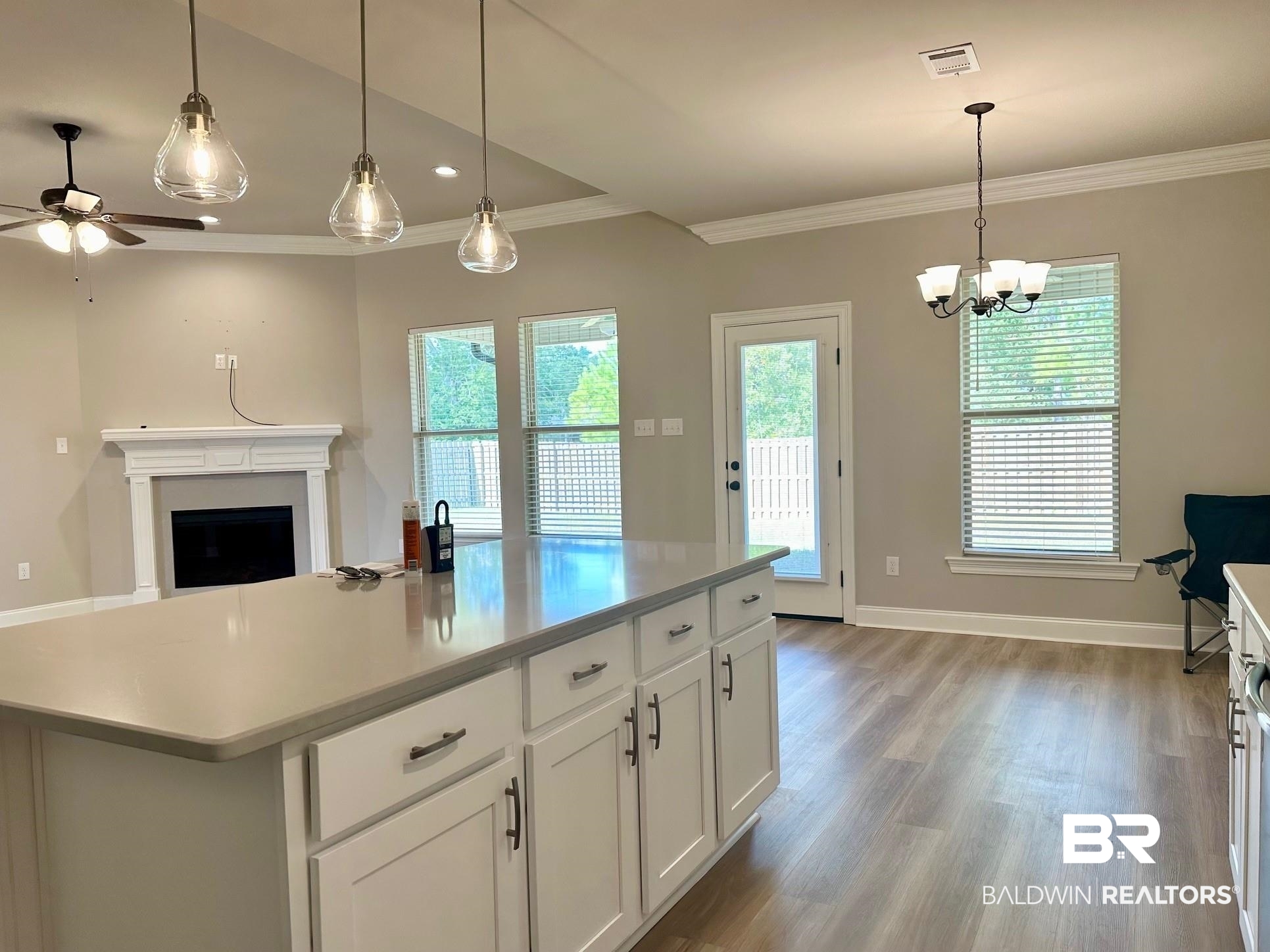 1009 Ruisseau Drive Foley, AL 36535 - Photo 29 of 55 Kitchen featuring a kitchen island, ceiling fan with notable chandelier, white cabinetry, light hardwood / wood-style floors, and decorative light fixtures