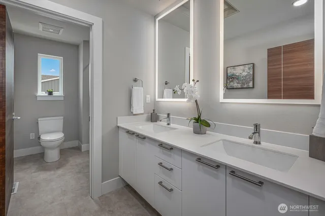 a bathroom with a double vanity sink a toilet and a mirror