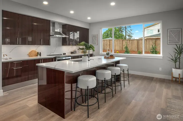 a kitchen with stainless steel appliances granite countertop wooden floor a stove a sink dishwasher a dining table and chairs with wooden floor