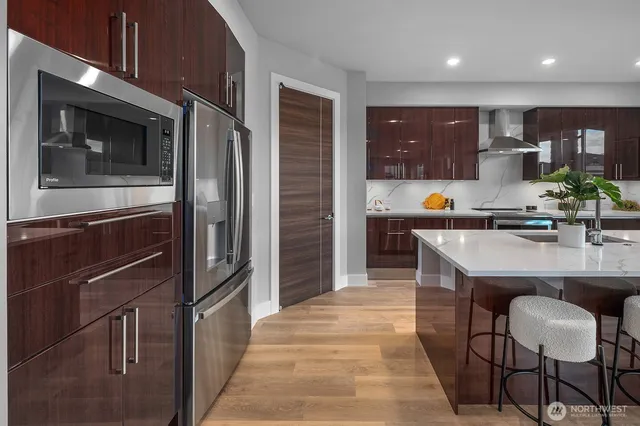 a kitchen with stainless steel appliances kitchen island granite countertop a refrigerator a stove and a sink with wooden floor