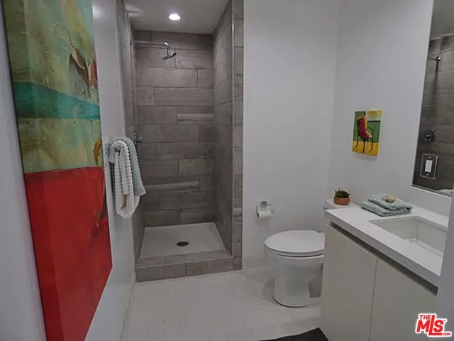 a bathroom with a granite countertop sink a toilet and shower