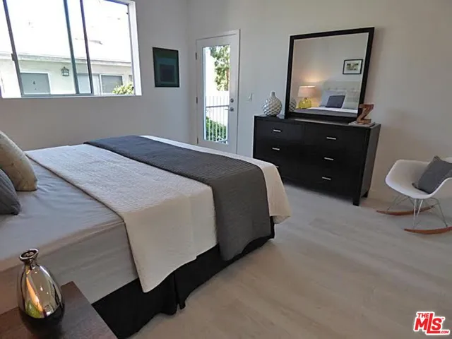 a bedroom with a bed and a dresser next to a window