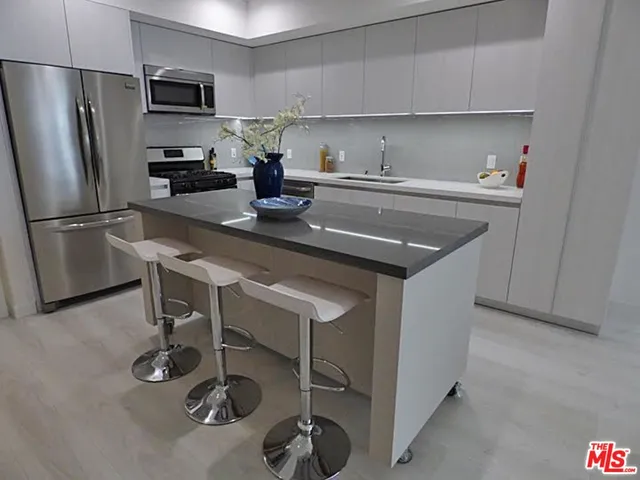 a kitchen with a sink a refrigerator and chairs