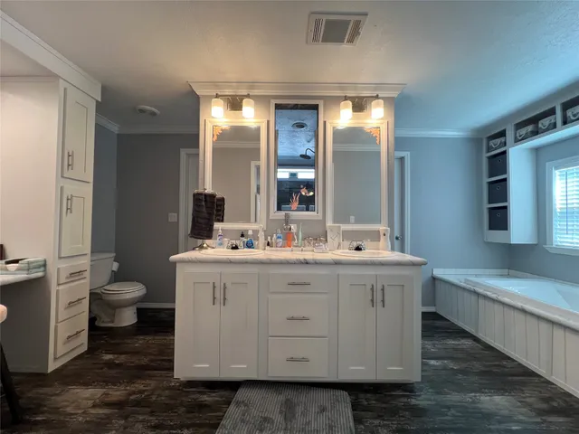 a spacious bathroom with a double vanity sink a toilet and a mirror