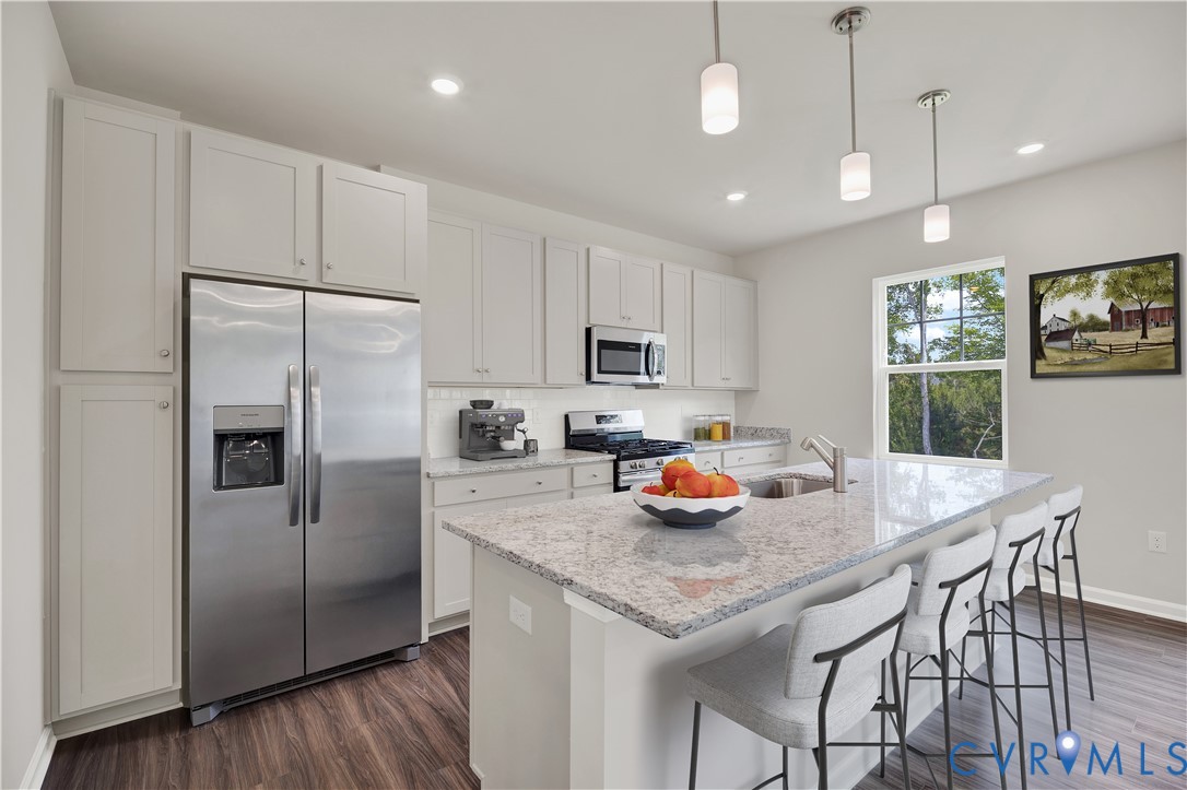 6454 Fennec Run Moseley, VA 23120 - Photo 2 of 23 a kitchen with stainless steel appliances granite countertop a sink a stove a refrigerator cabinets and a dining table with wooden floor