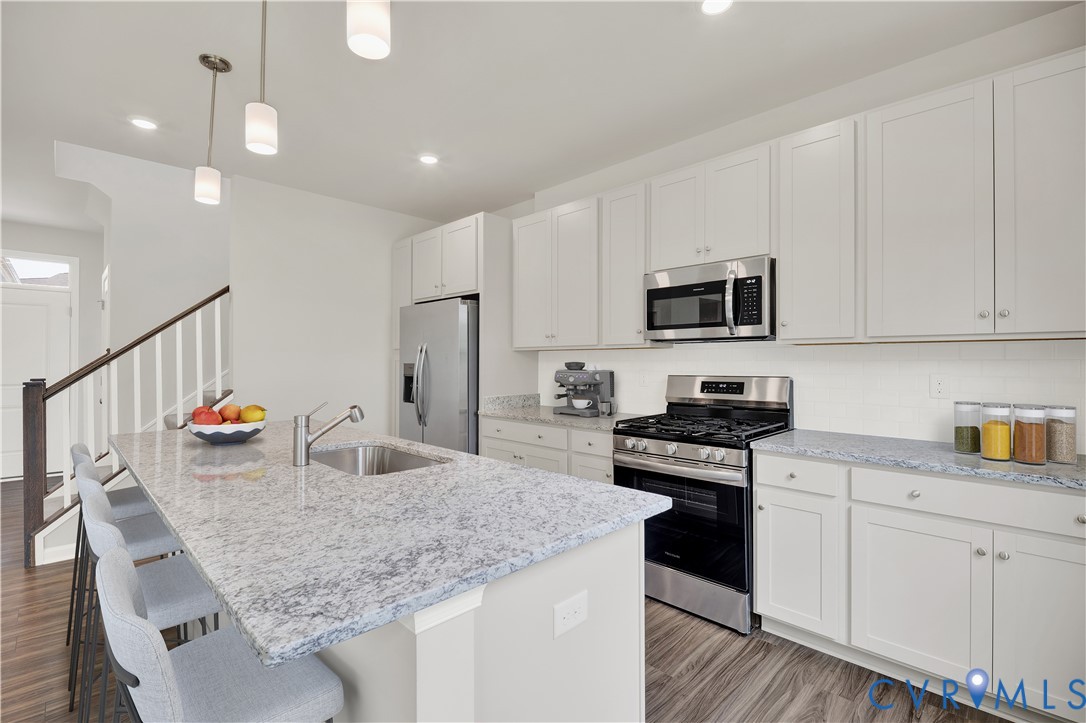 6454 Fennec Run Moseley, VA 23120 - Photo 4 of 23 a kitchen with stainless steel appliances kitchen island granite countertop a stove a sink and white cabinets