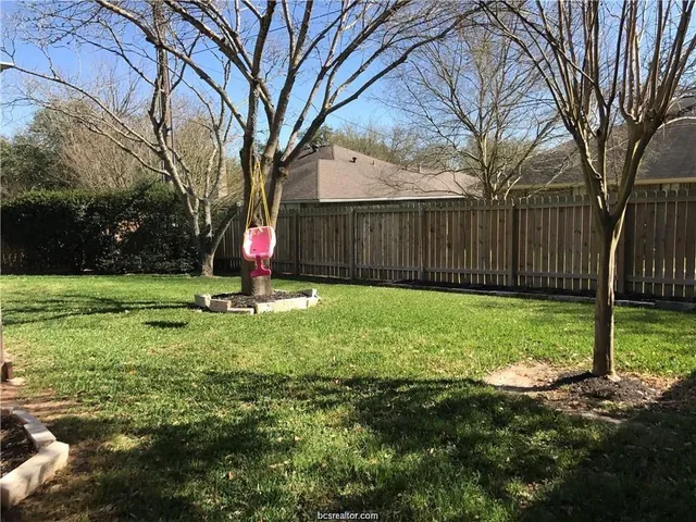a view of a backyard with table and chairs and a large tree