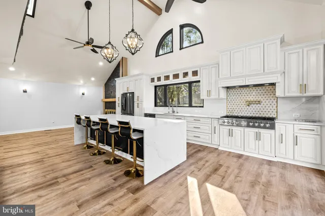 a large white kitchen with kitchen island a stove a sink a dining table and chairs