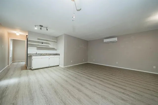 an empty room with wooden floor closet and windows