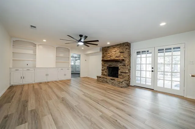 an empty room with wooden floor fireplace and windows