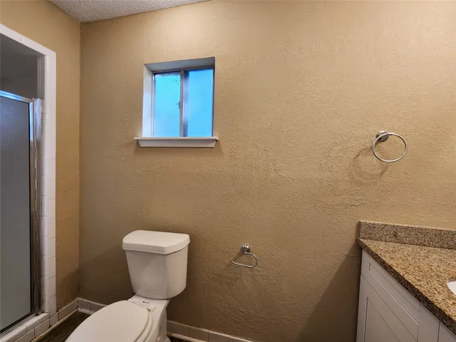 a bathroom with a granite countertop toilet and a sink