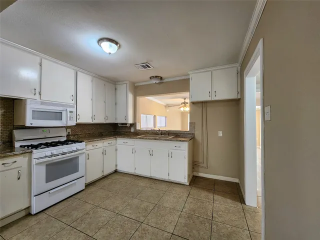 a kitchen with granite countertop white cabinets and white appliances