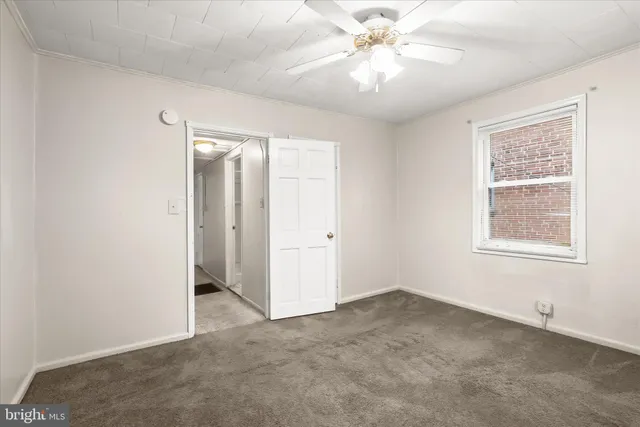 an empty room with chandelier fan and windows