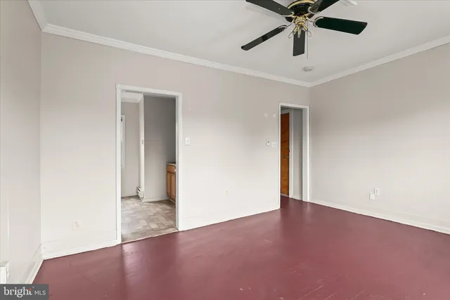 an empty room with chandelier fan and windows