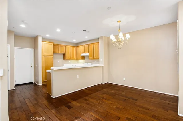 a dining room with wooden floor a chandelier a glass table and chairs