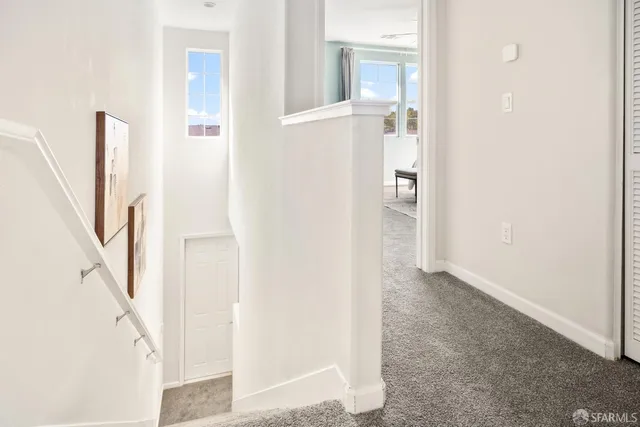 a view of a hallway with white walls and stairs