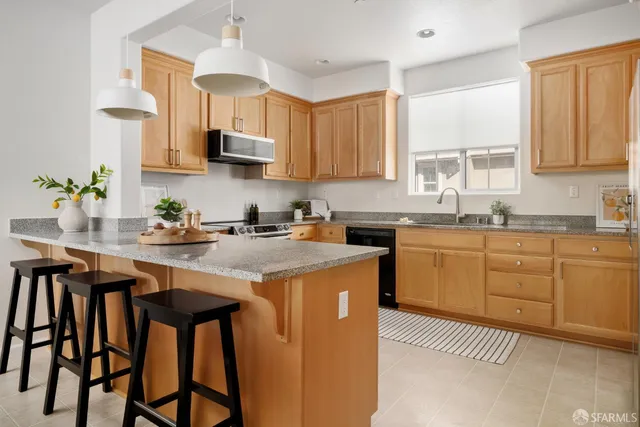 a kitchen with stainless steel appliances granite countertop a sink a stove a refrigerator cabinets and a dining table